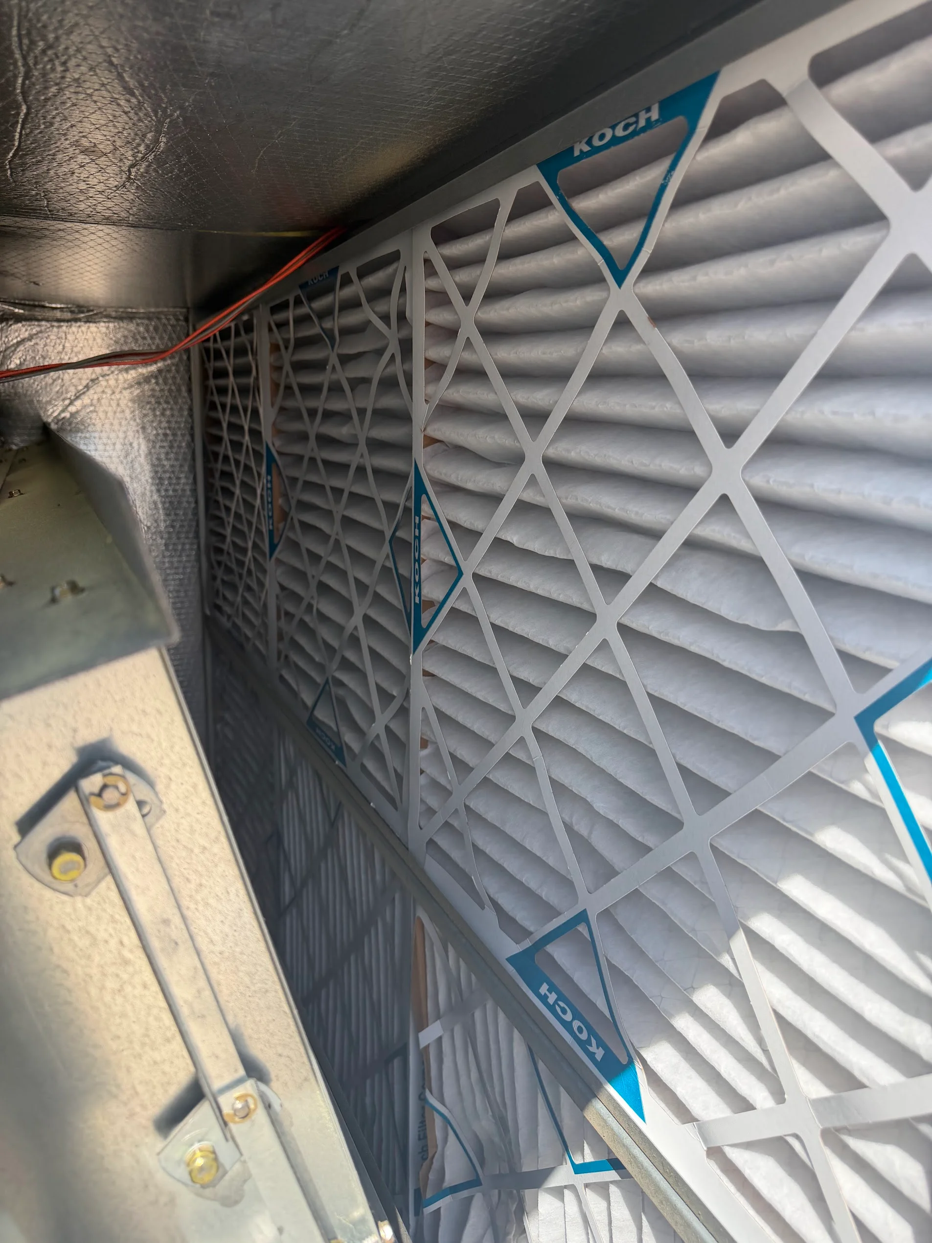 Pleated HVAC filters installed in furnace housing with electrical connections