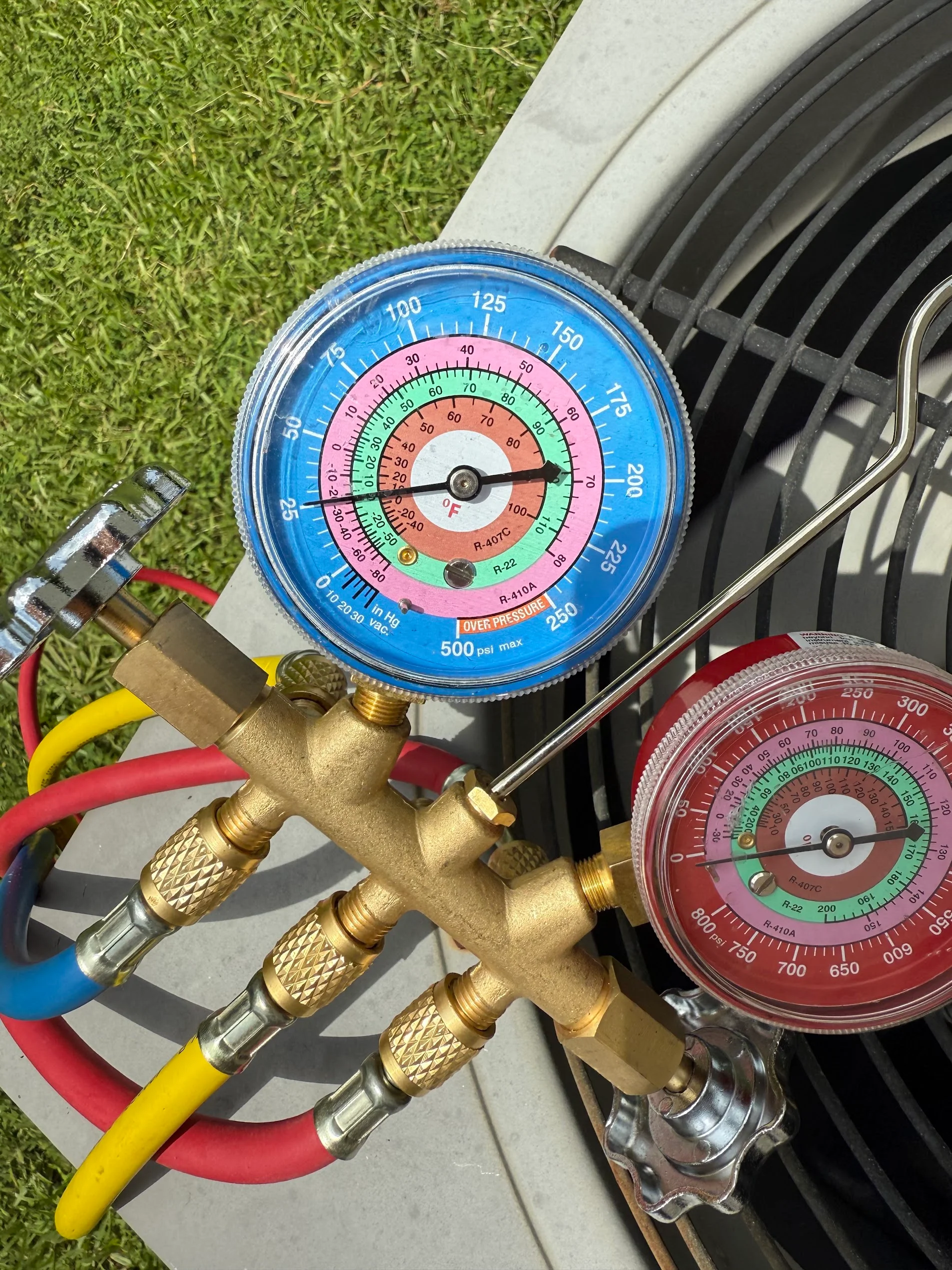 Dual-gauge manifold set with brass block, color-coded pressure gauges, and service hoses for HVAC refrigerant testing