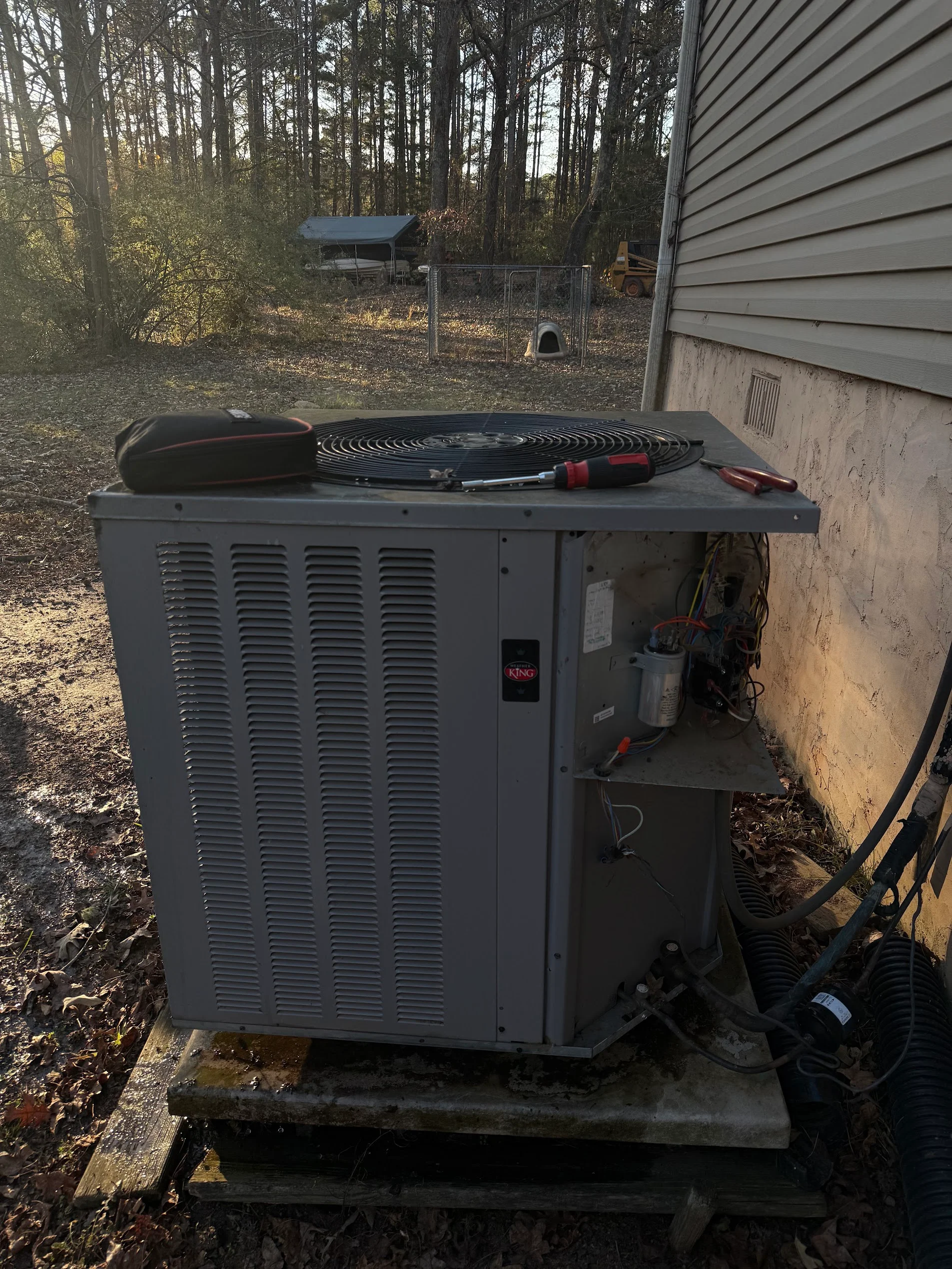 Gray heat pump unit on concrete pad with refrigerant lines and electrical connections installed