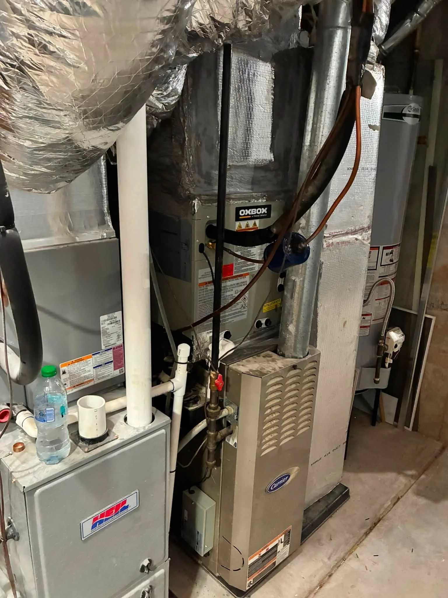 Installed furnace and air handler with insulated ducts, copper refrigerant lines, and sealed connections