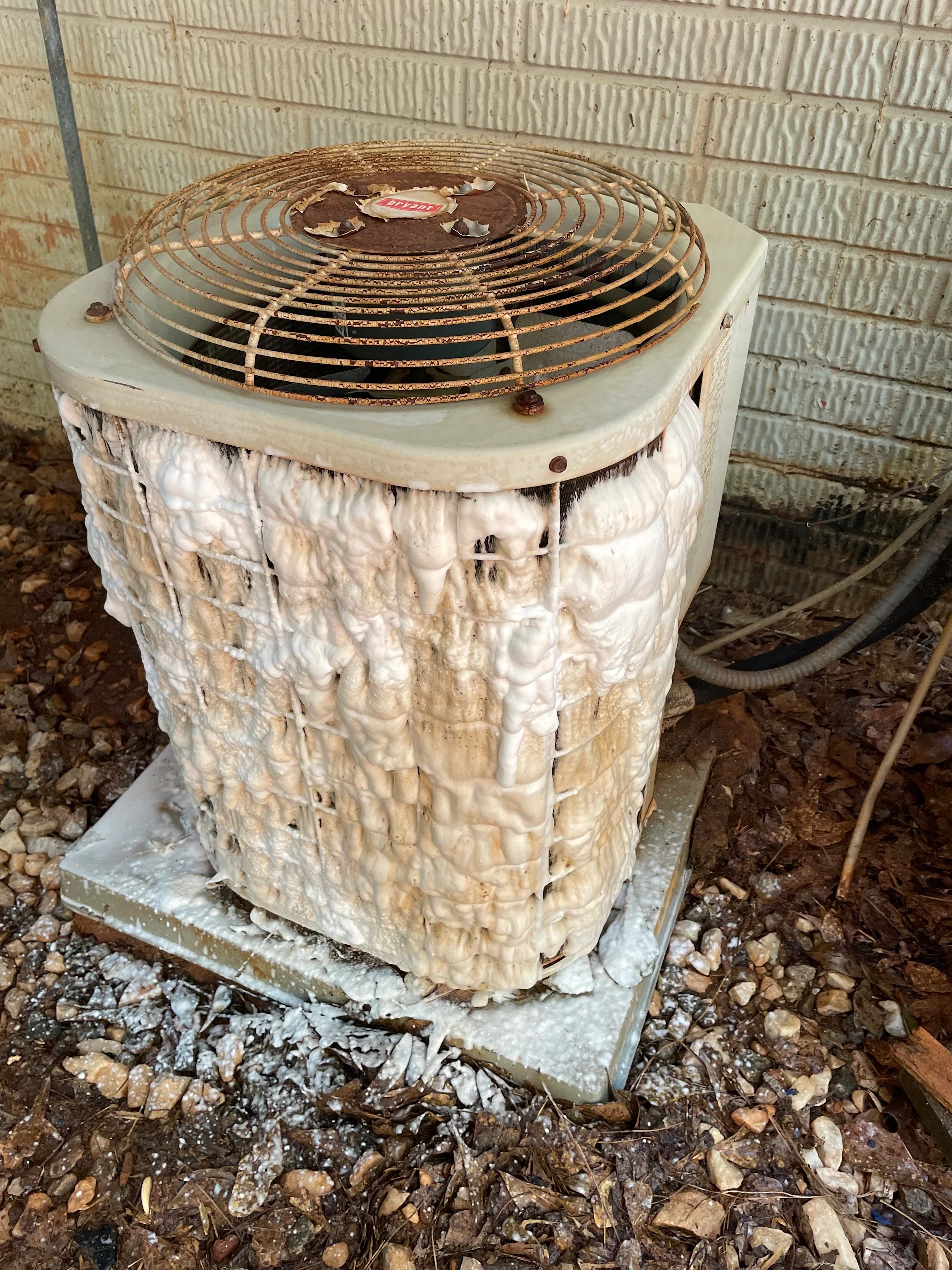 Corroded AC condenser unit with rusted fan guard and damaged white casing before replacement