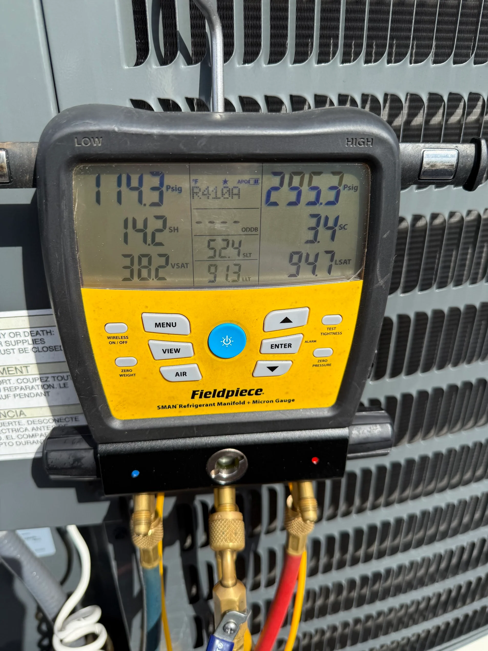 Fieldpiece SMAN refrigerant manifold gauge displaying dual pressure and temperature readings on HVAC system