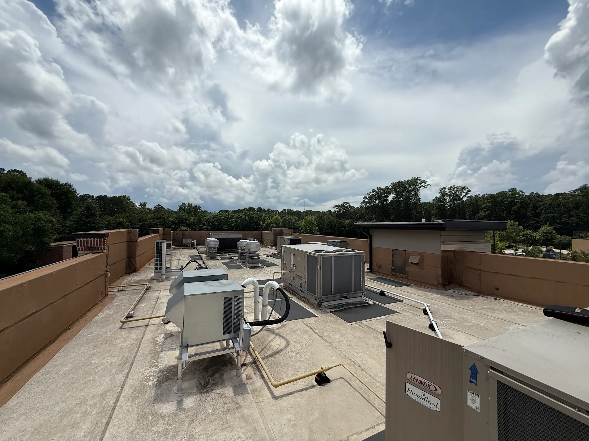 Commercial rooftop with multiple HVAC units, condensers, and ductwork on concrete deck