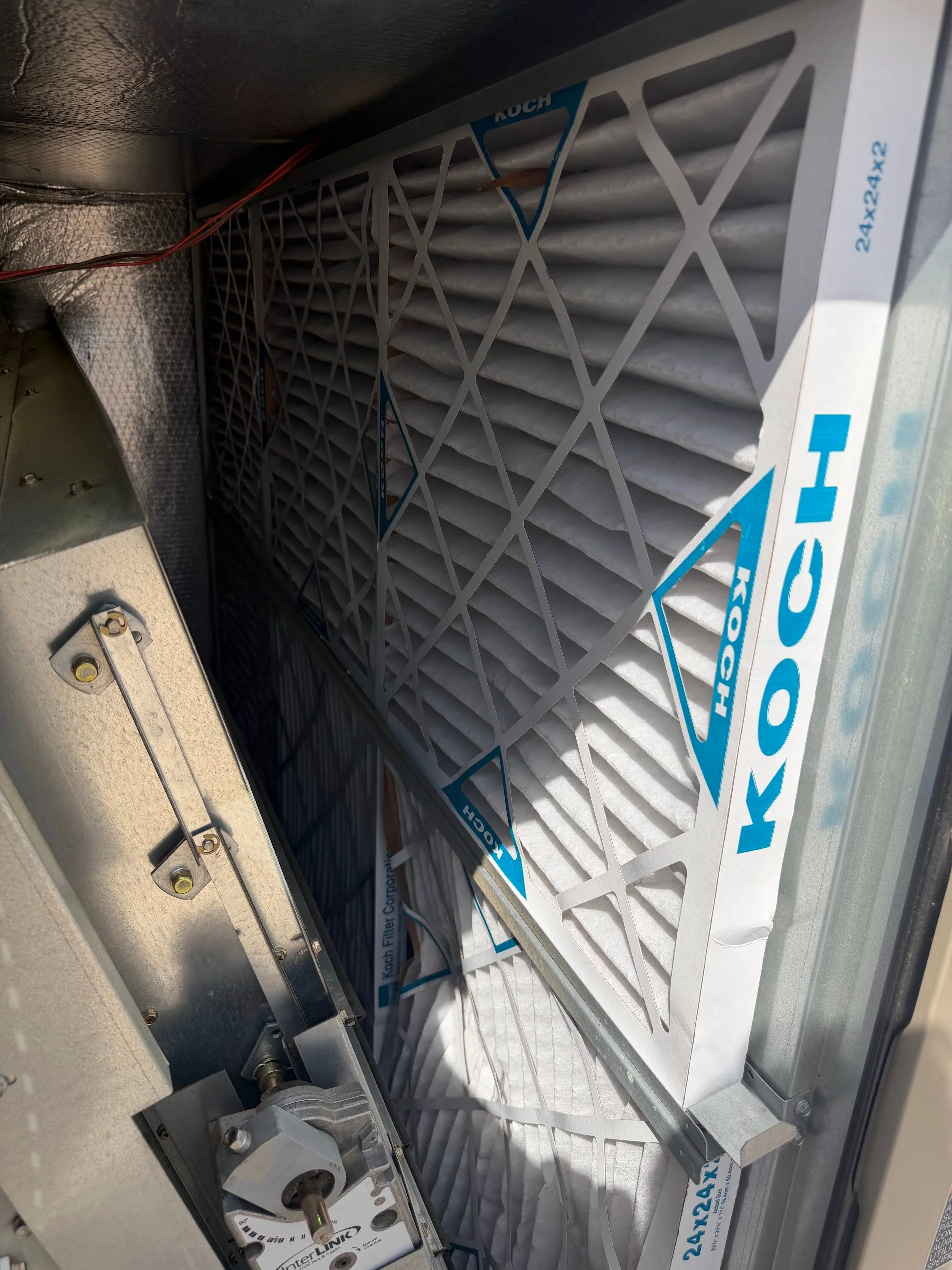 A Legacy HVAC Services technician replacing a dirty air filter inside a residential HVAC return vent in a Hampton, GA home. The old filter shows heavy gray dust buildup consistent with Georgia pollen and red clay particulate.